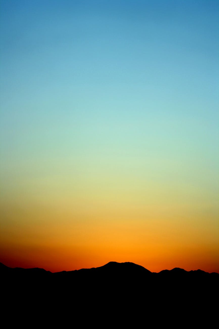A stunning sunset creates a silhouette of distant mountains under a vivid gradient sky.