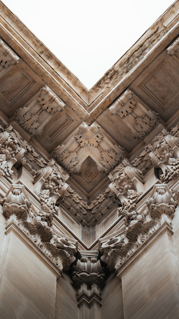 Close-up view of intricate stone carvings in a neo-classical style at an architectural corner.