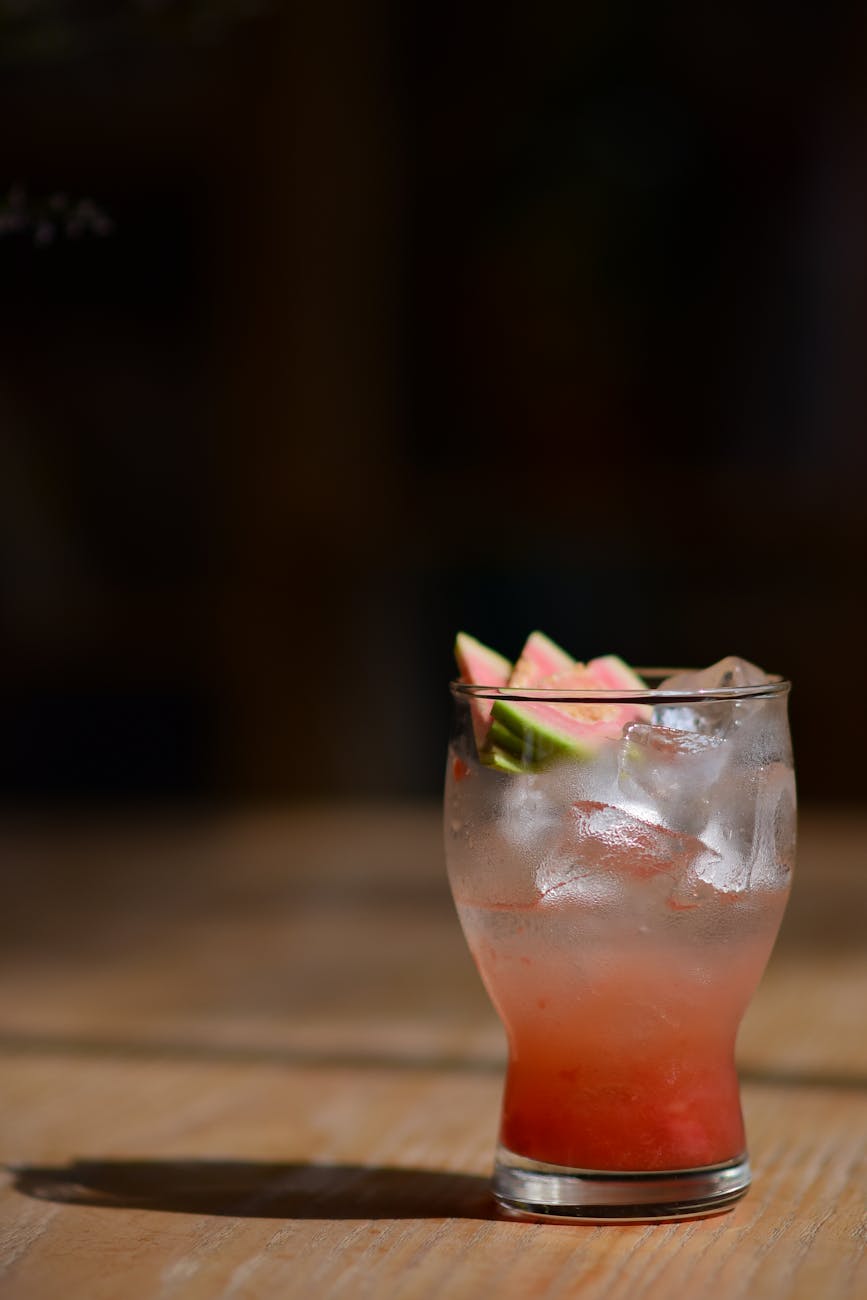 Chilled watermelon cocktail with ice and lime on a wooden table, perfect for summer refreshment.