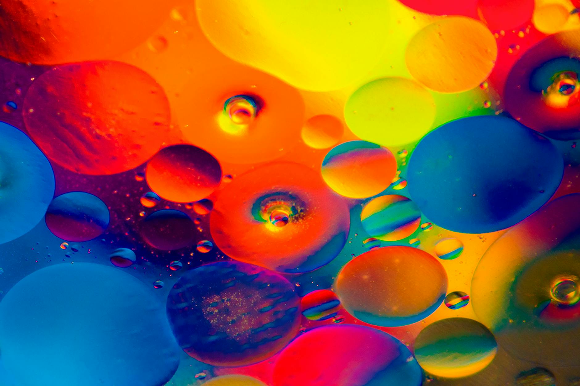 Colorful abstract artwork featuring vibrant bubbles of oil immersed in water, showcasing dynamic color patterns.