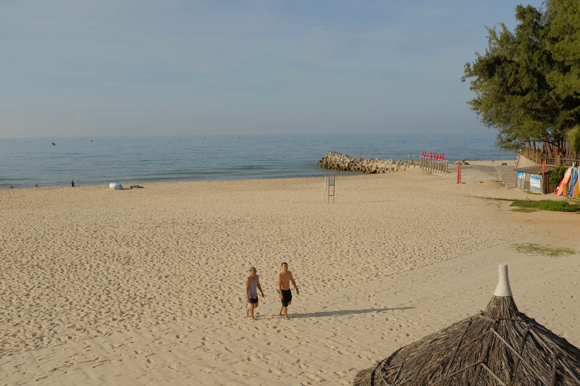 Two people walking along the scenic sandy beach of Binh Thuan, Vietnam on a sunny day.