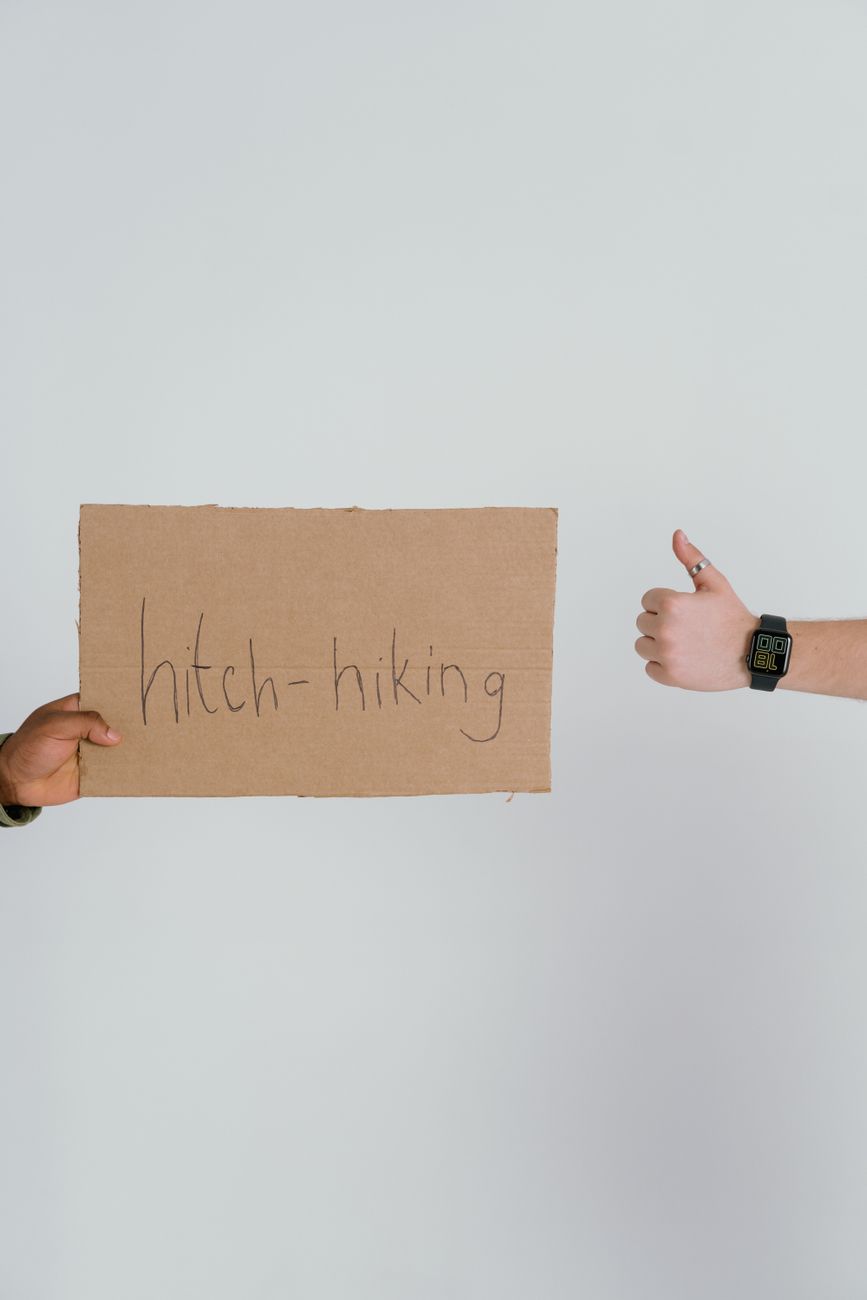 Simple hitchhiking concept with a cardboard sign and thumbs up gesture, ideal for travel themes.