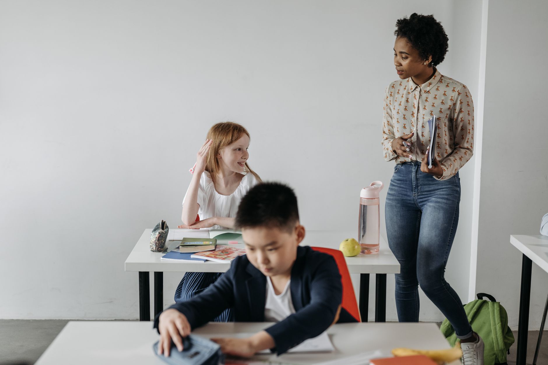 Teacher assisting diverse students in a classroom environment, promoting education and learning.