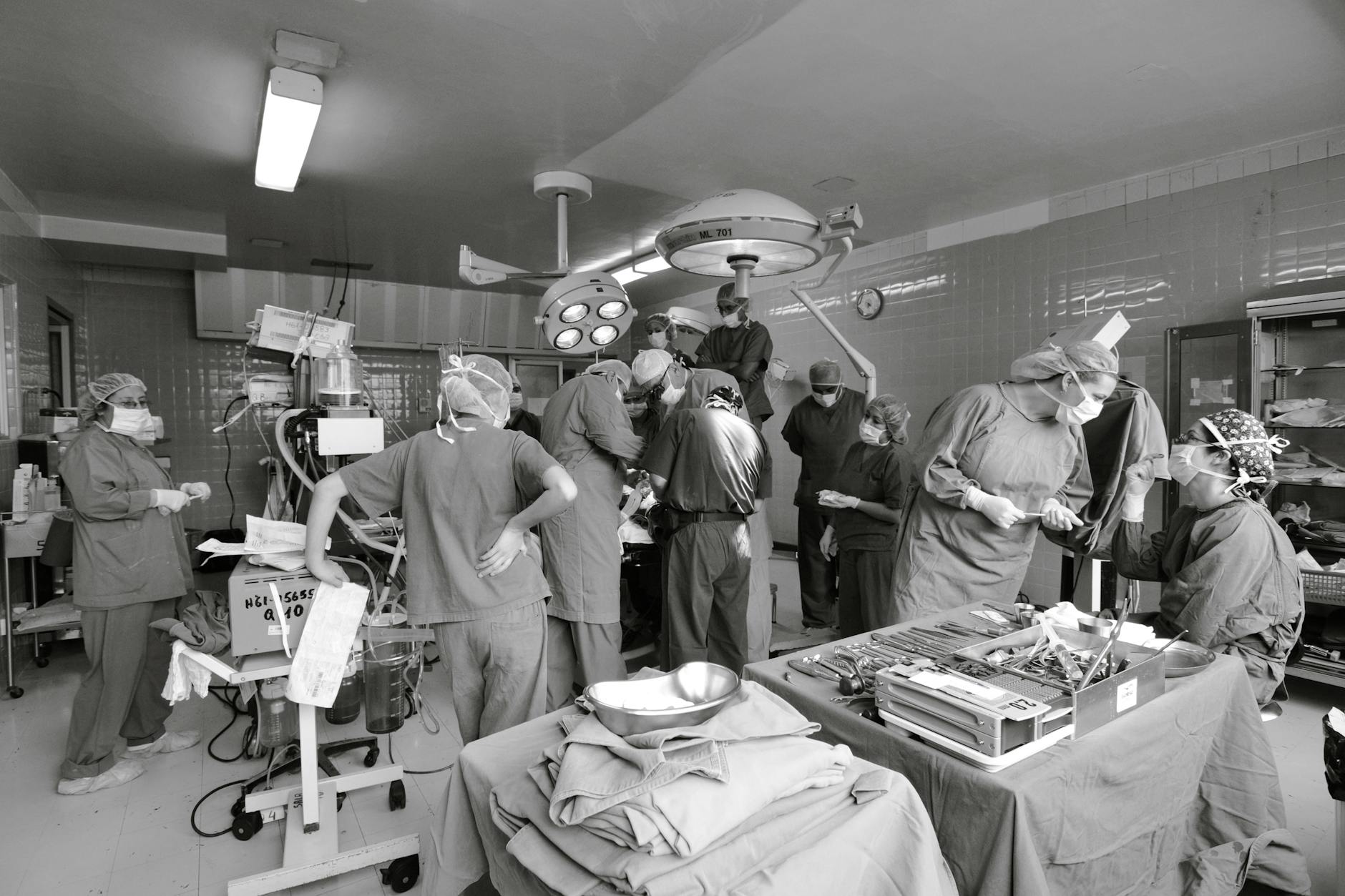 Surgeons and medical staff performing surgery in a busy operating room, emphasizing teamwork.