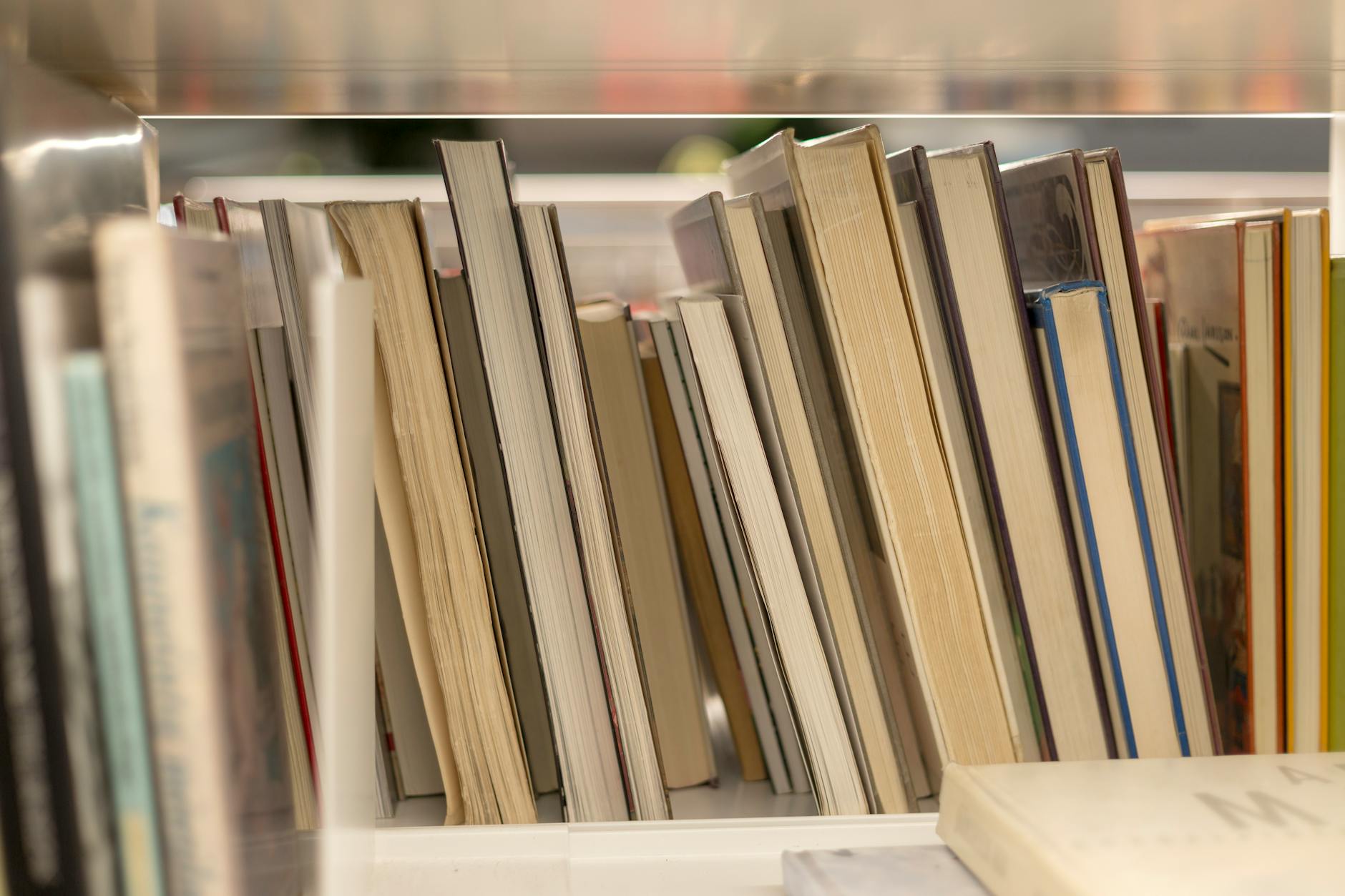 A close-up view of various books stacked vertically on a library shelf.