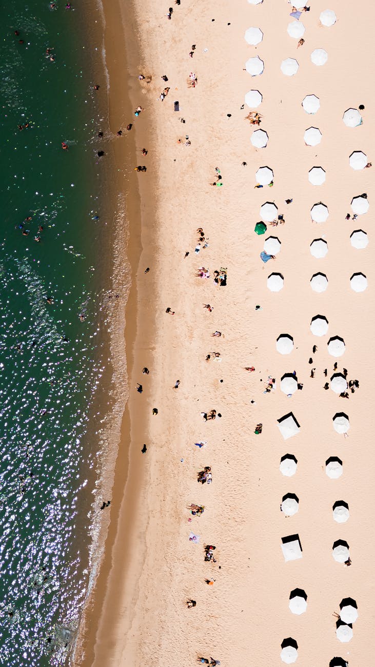 Aerial snapshot capturing a vibrant beach scene with umbrellas and ocean waves.