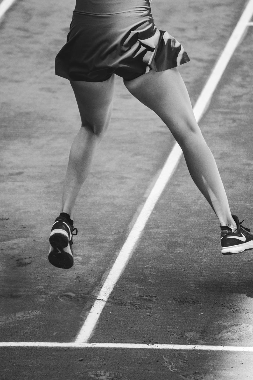 Black and white photo of an athlete in mid-jump on a sports track, highlighting dynamic movement.