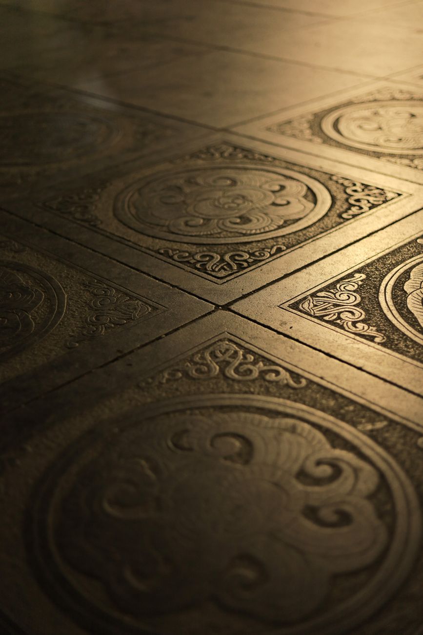 Close-up of ornate Vietnamese floor tiles with detailed designs and warm lighting.