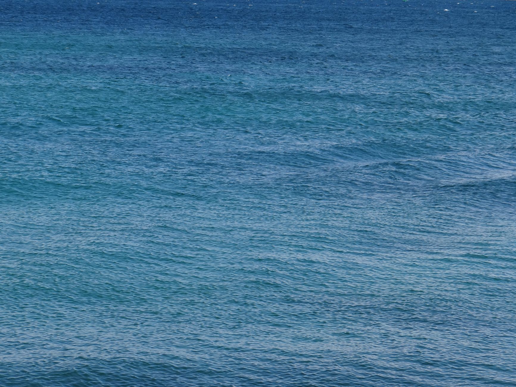 A serene view of calm ocean waves with varying blue hues, perfect for backgrounds or nature themes.