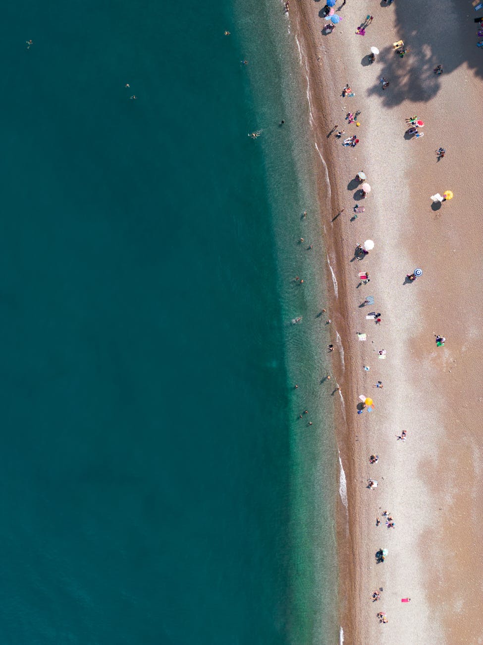 Aerial view of a crowded beach with umbrellas and people on a sunny summer day, offering perfect vacation vibes.