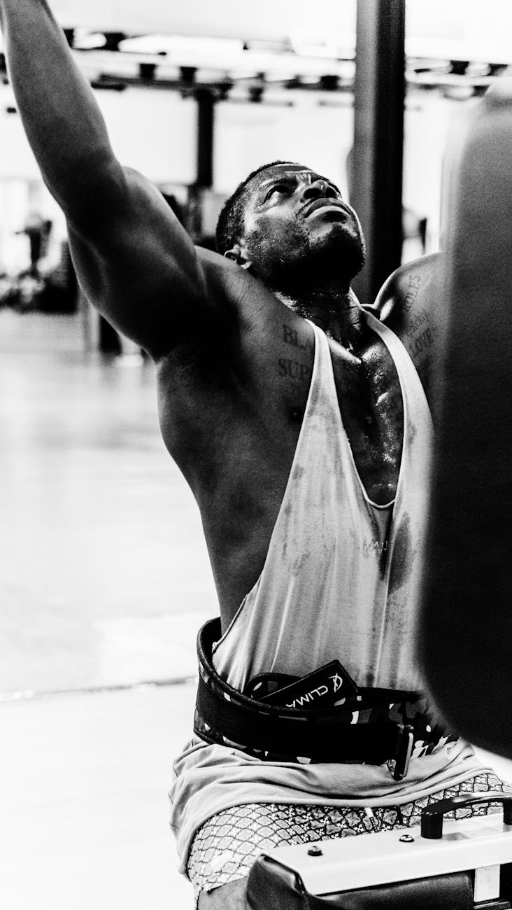 Sweaty man in gym lifting weights, showcasing intense effort and determination.