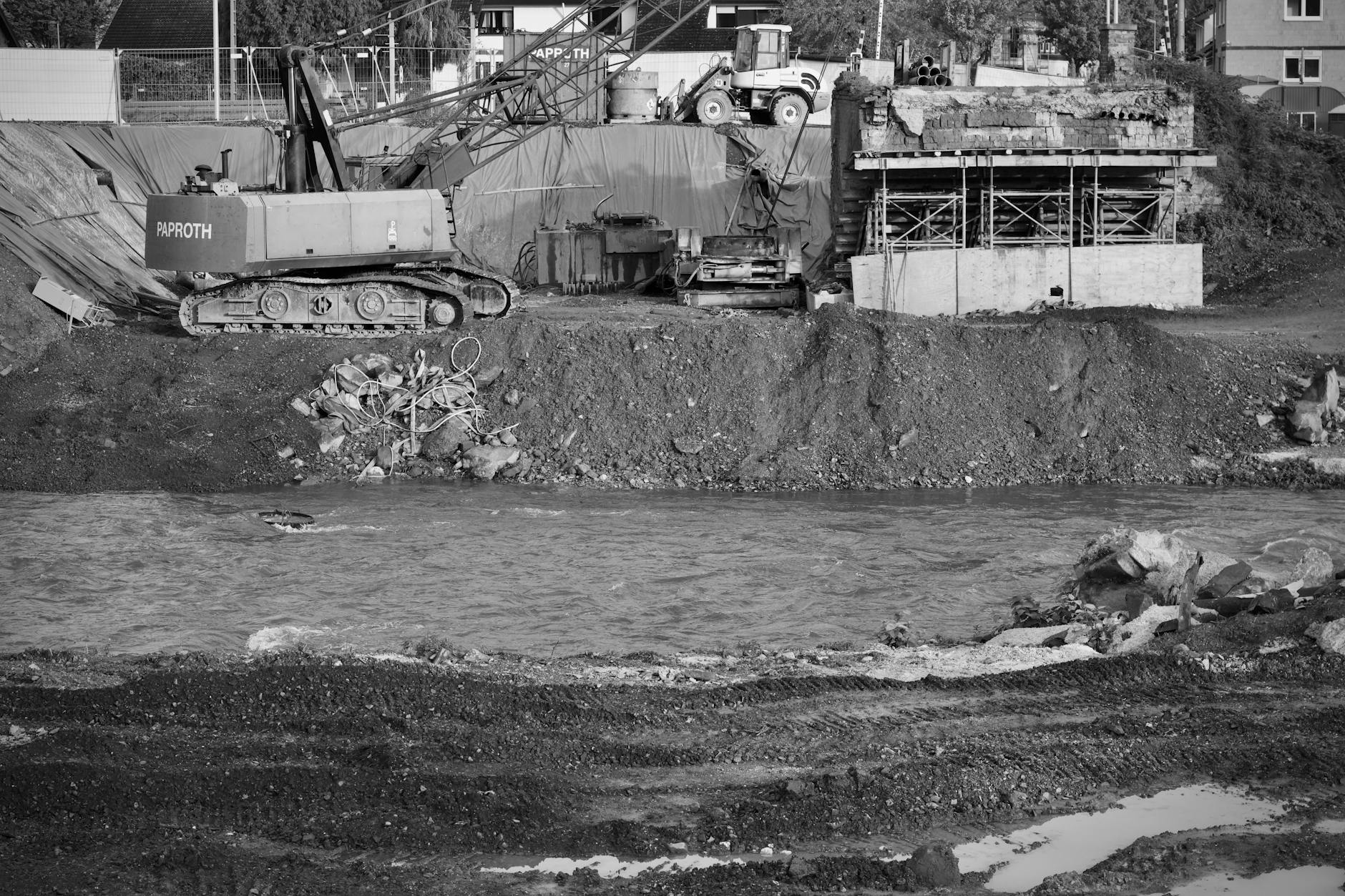 A monochrome depiction of an active construction site featuring an excavator.