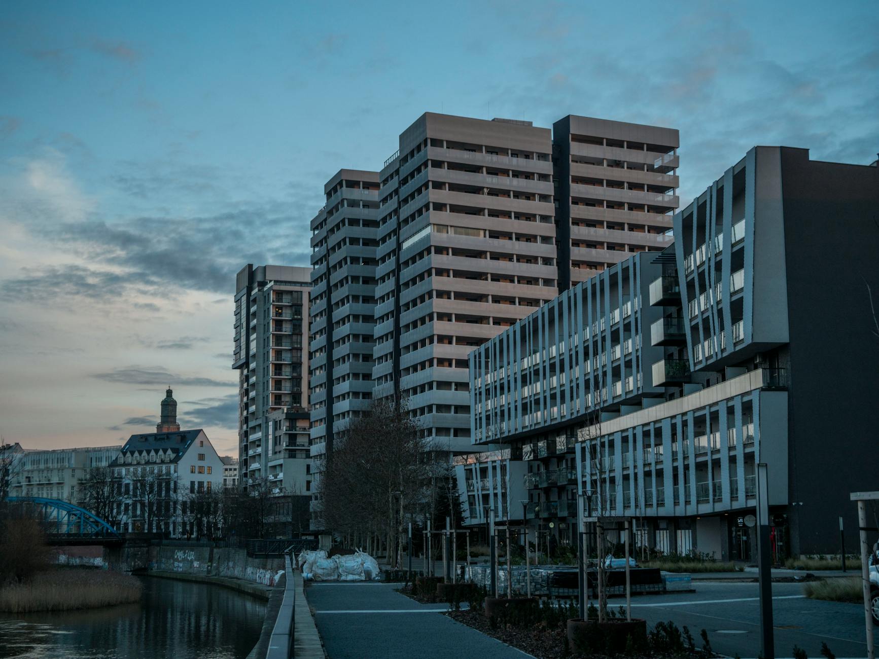 Cityscape of Wrocław, Poland featuring modern buildings by the river at dusk.