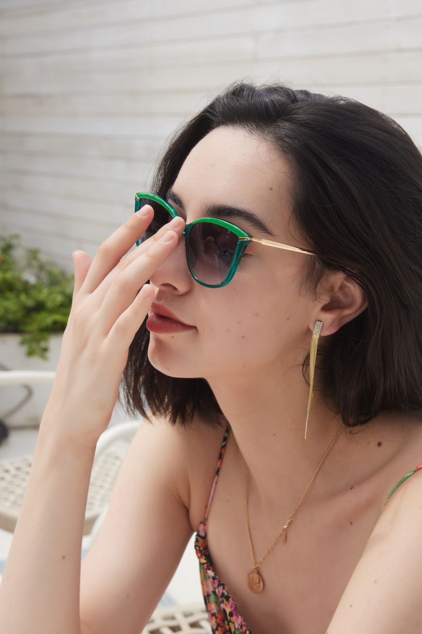 Chic woman in sunglasses poses outdoors, showcasing fashion and elegance.