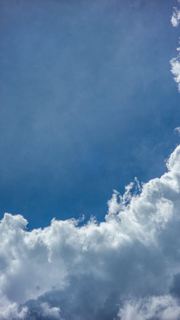 Vivid blue sky with dynamic, fluffy white clouds creating a serene and inspiring cloudscape.