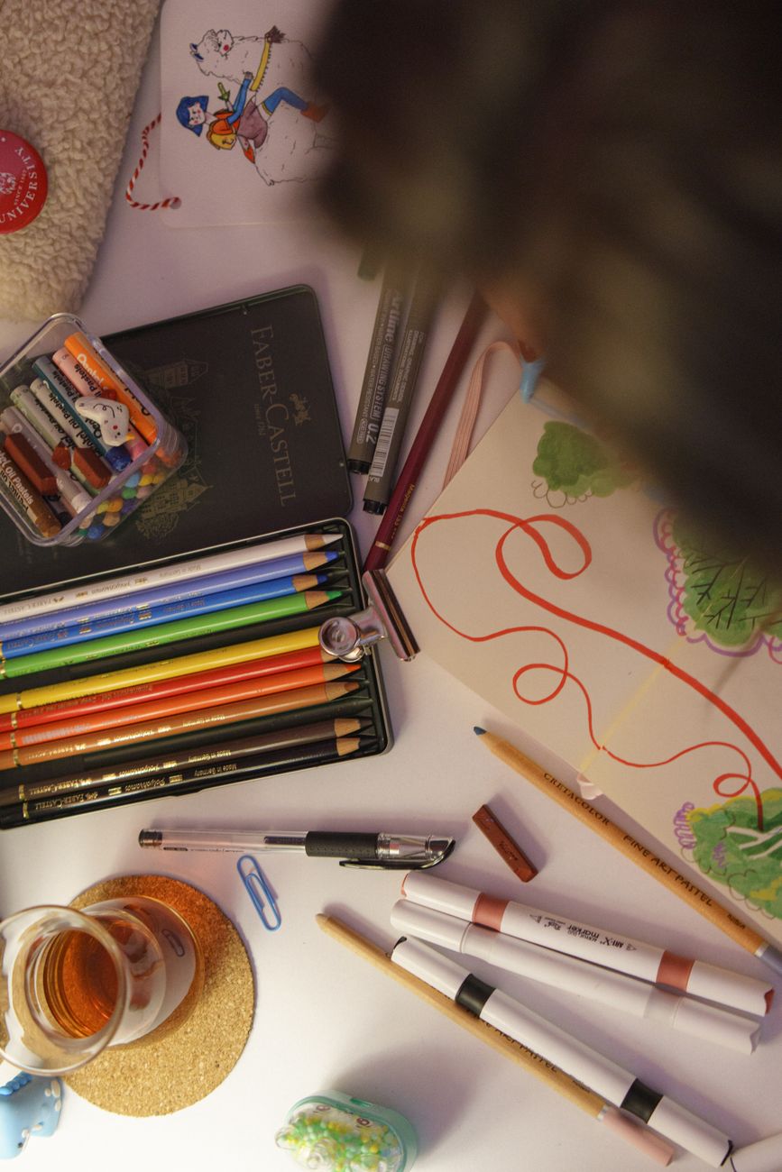 Top view of art supplies with colored pencils, markers, and sketchbook, ideal for creative projects.