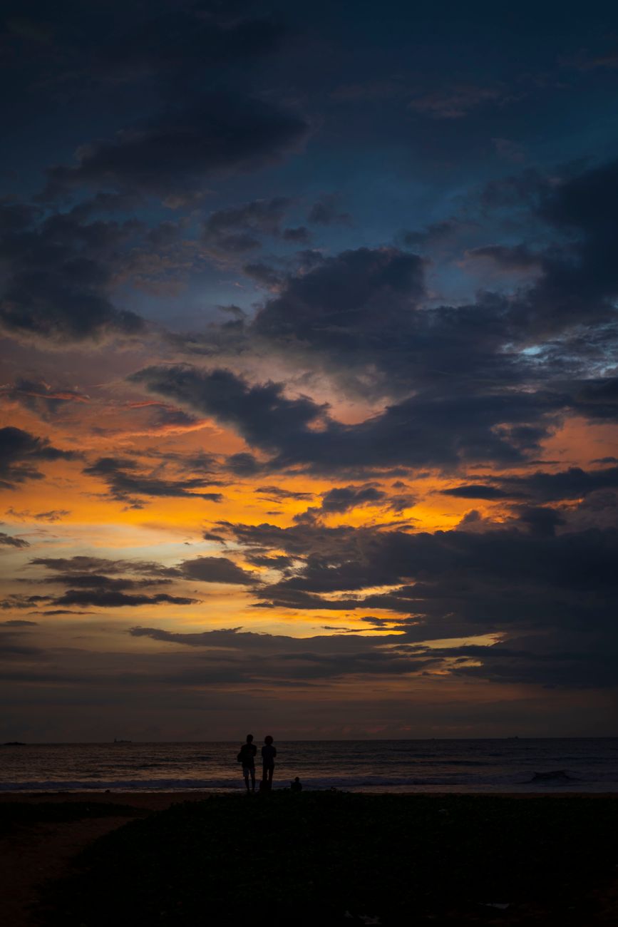 Beautiful silhouettes against a vibrant sunset sky over the ocean in Western Province, Sri Lanka.