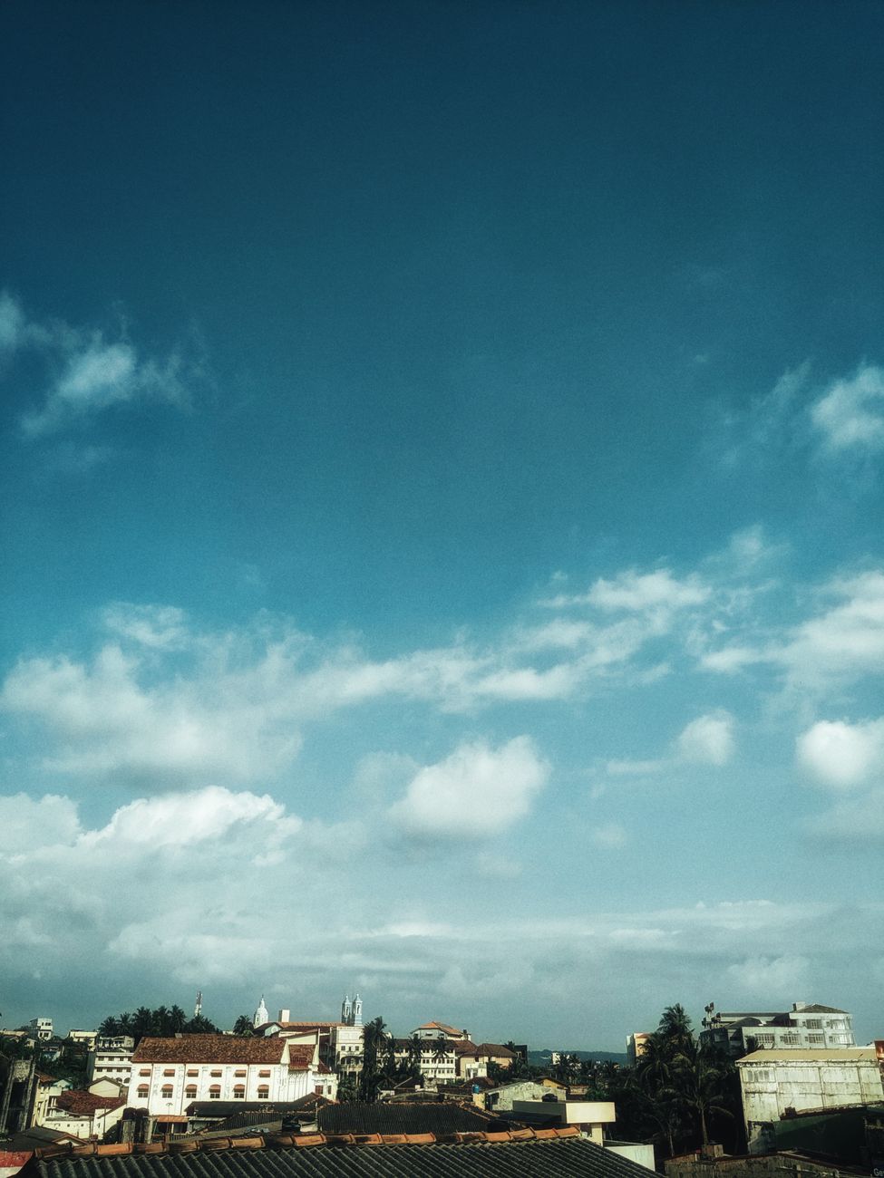 Beautiful urban skyline with historic architecture under a bright blue sky with clouds.