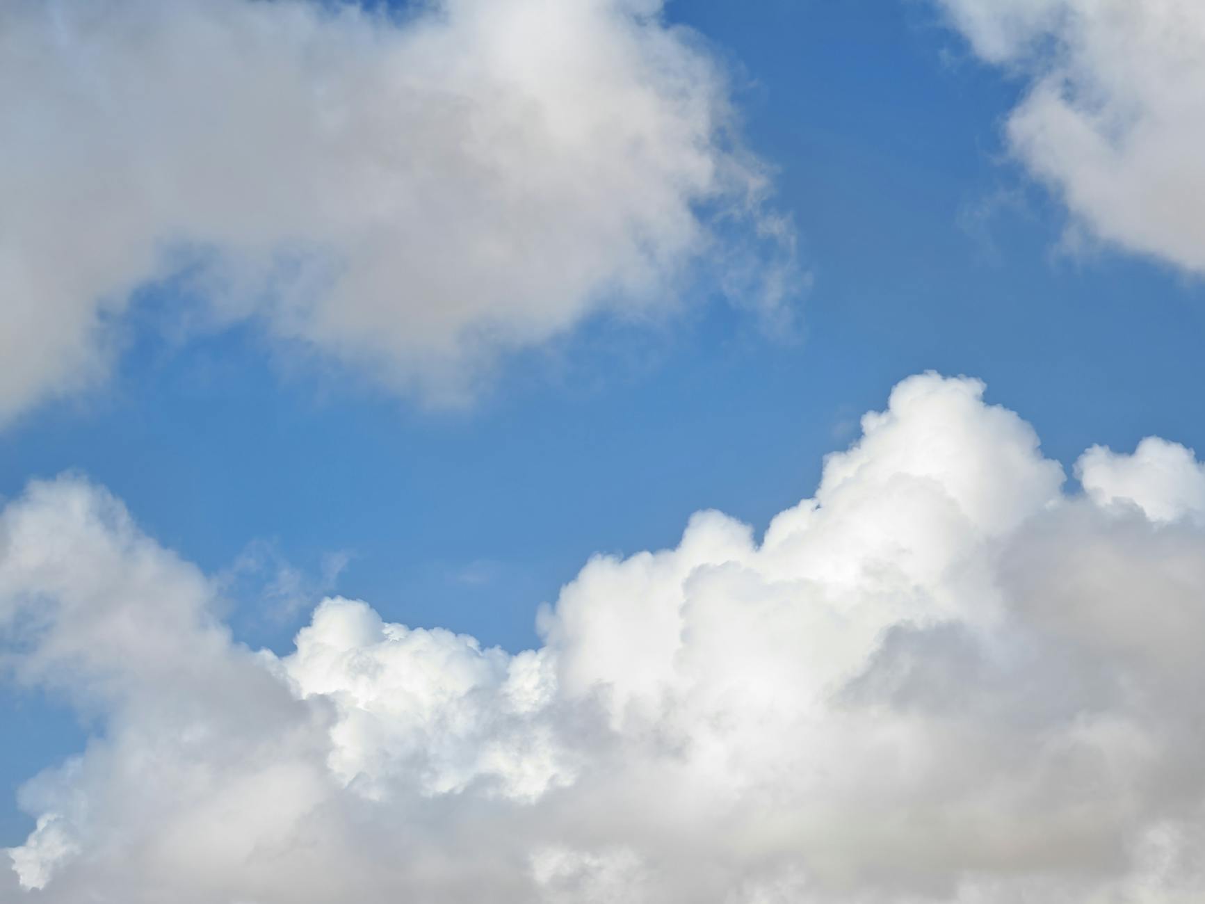 A serene sky filled with fluffy white clouds against a vivid blue background.
