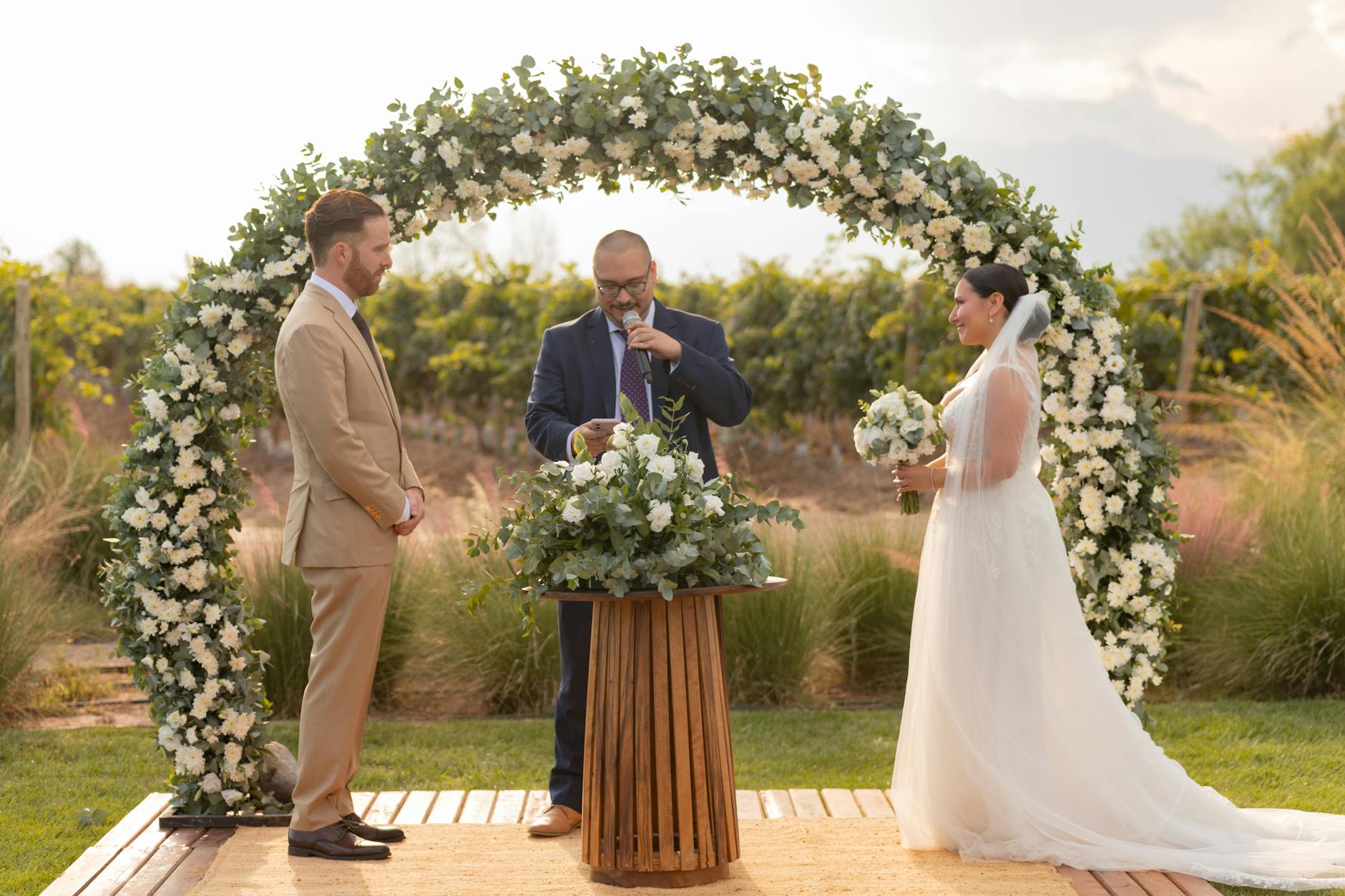 Bride and groom exchange vows under a floral arch in Mendoza, Argentina vineyard.