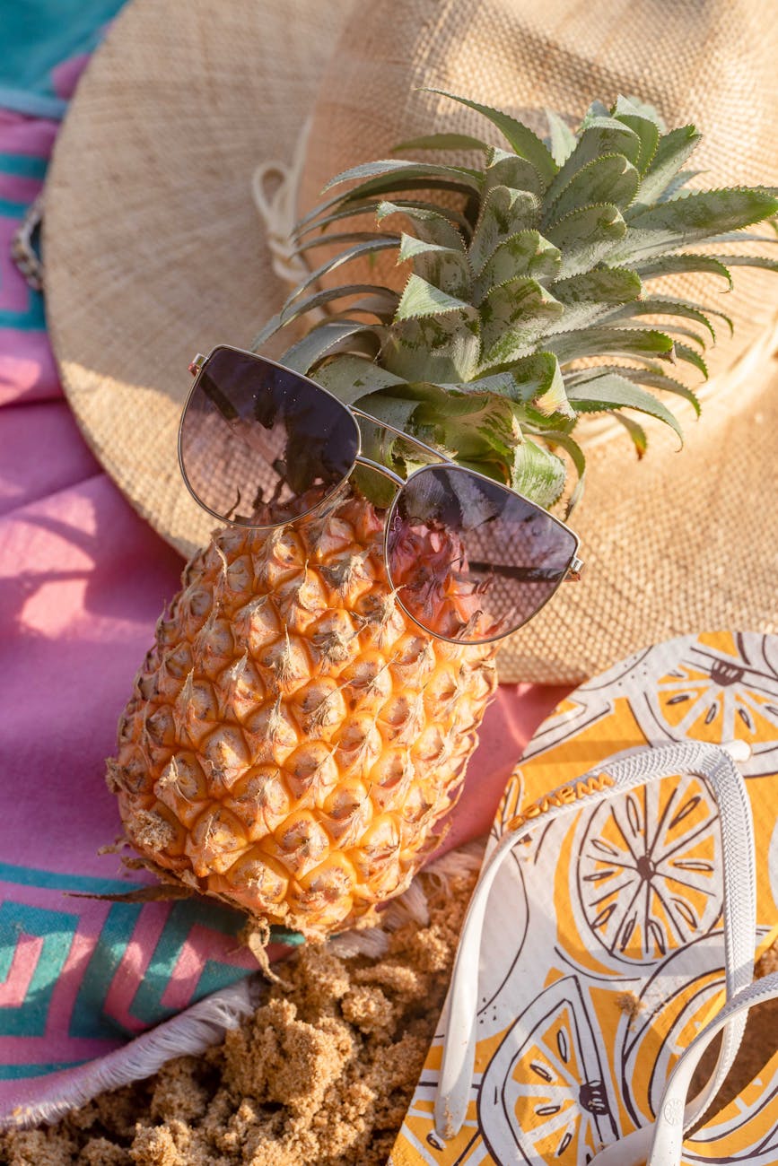 Stylish pineapple in sunglasses on a beach with summer accessories.