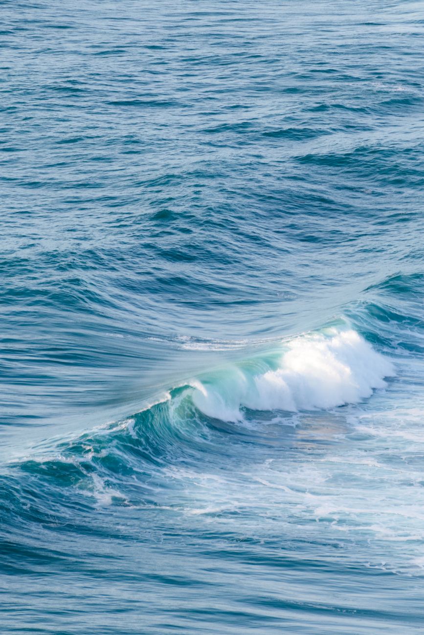 Captivating ocean waves rolling on a calm sea under soft light, perfect for nature themes.