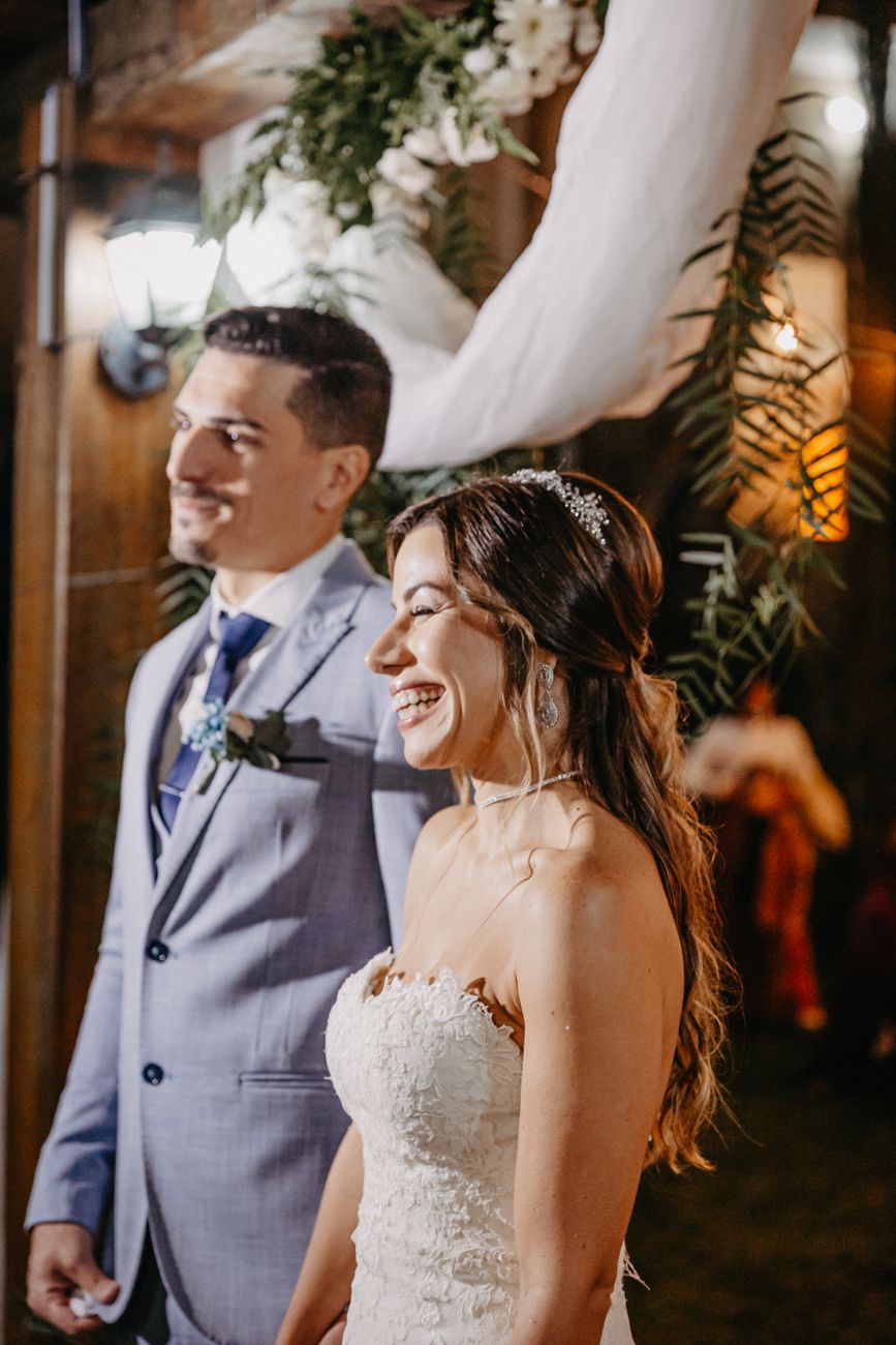 Smiling bride and groom in elegant attire during their wedding ceremony indoors.