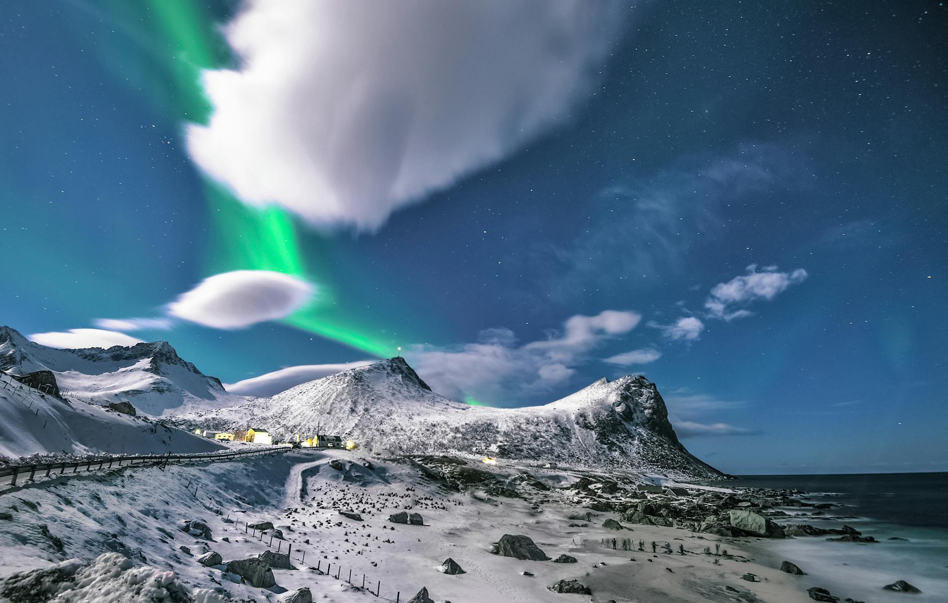 Snowy mountains under the aurora borealis in Myrland, Nordland, Norway, showcasing a serene winter night.