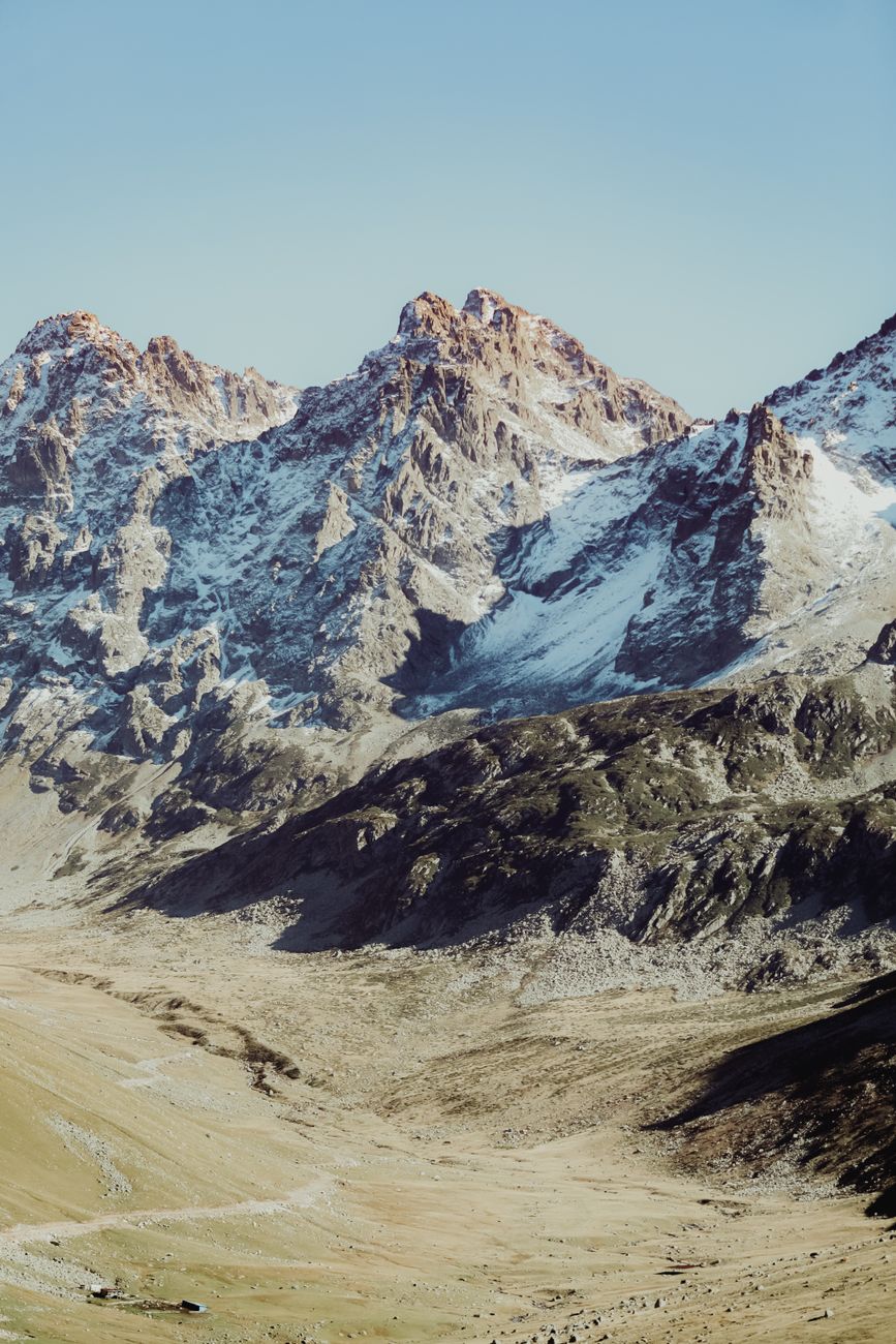A breathtaking view of rugged snow-capped mountains under a clear blue sky. Ideal for adventure and nature themes.