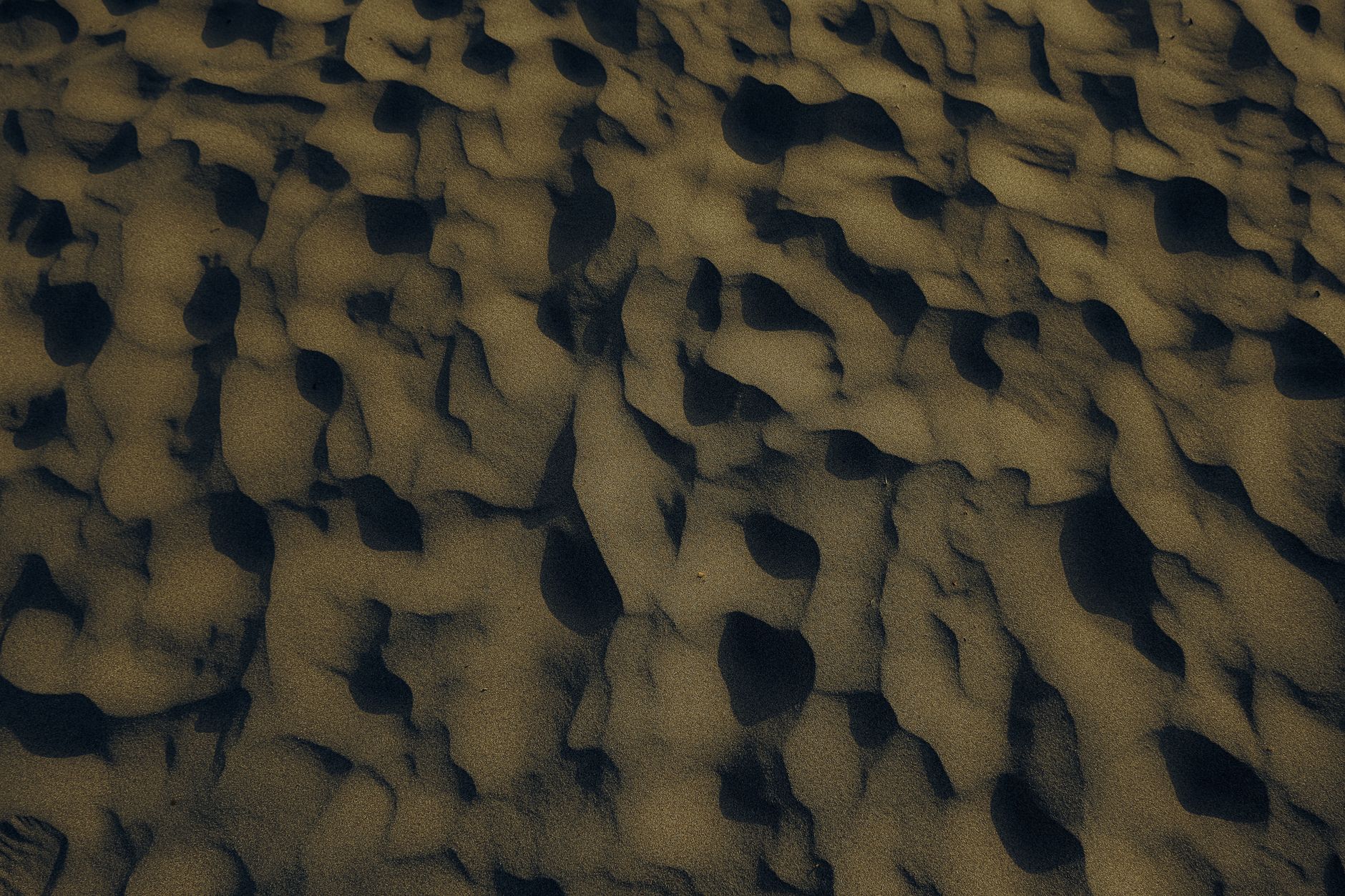 Aerial view of intricate sand patterns on a beach at sunset, capturing nature's artwork.