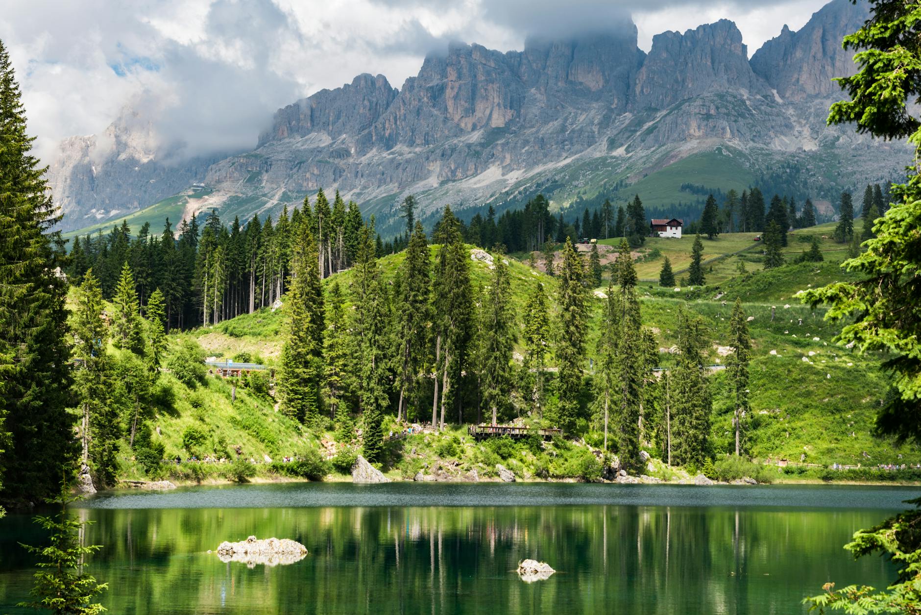 A tranquil view of Lake Carezza with reflecting waters and Dolomite mountains in Trentino, Italy.