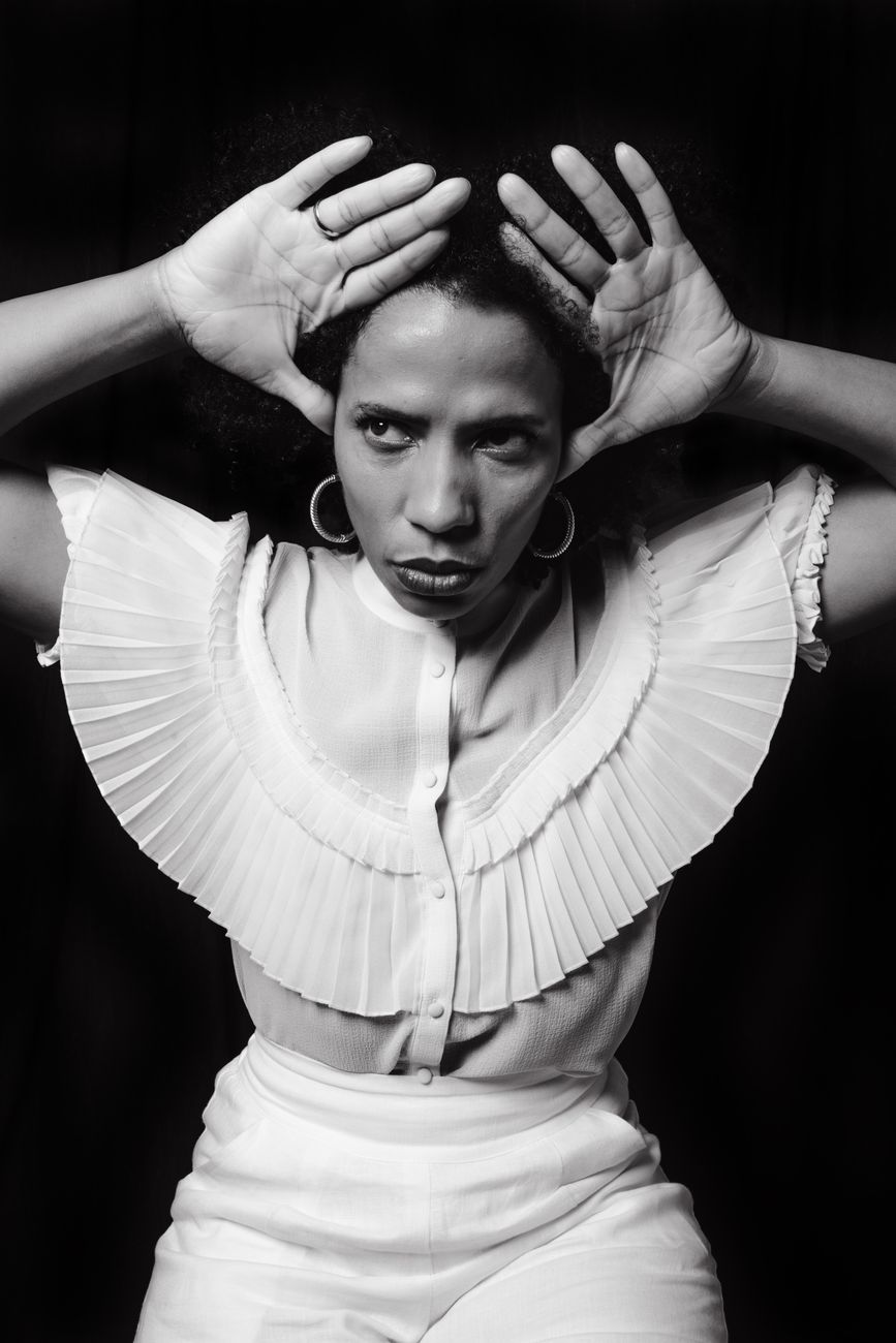 Striking monochrome portrait of a black woman with afro hair and hoop earrings.