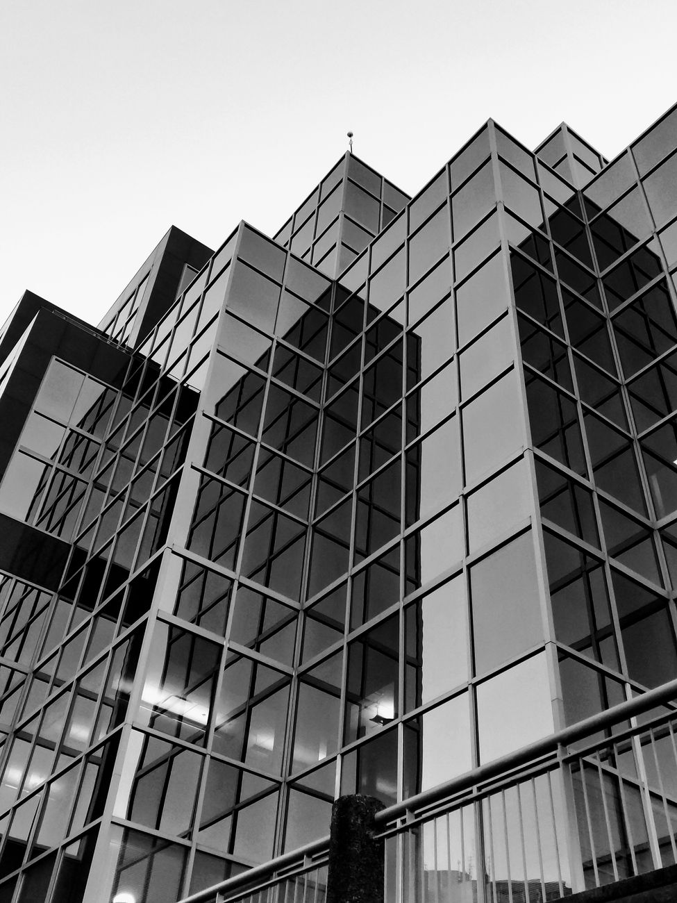 Low-angle black and white photo of a modern glass skyscraper's facade in an urban setting.