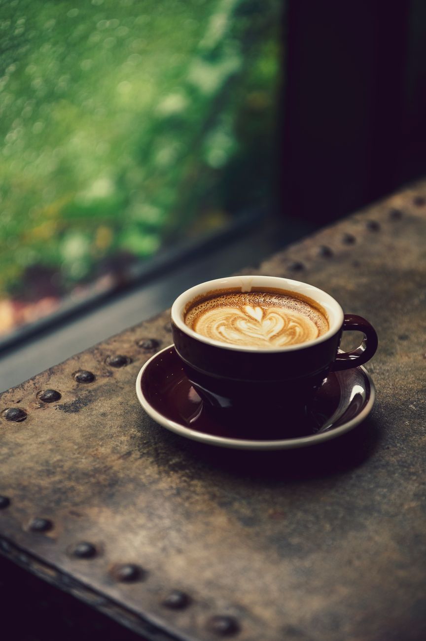 A beautifully crafted cup of latte with heart-shaped art on a rustic table.