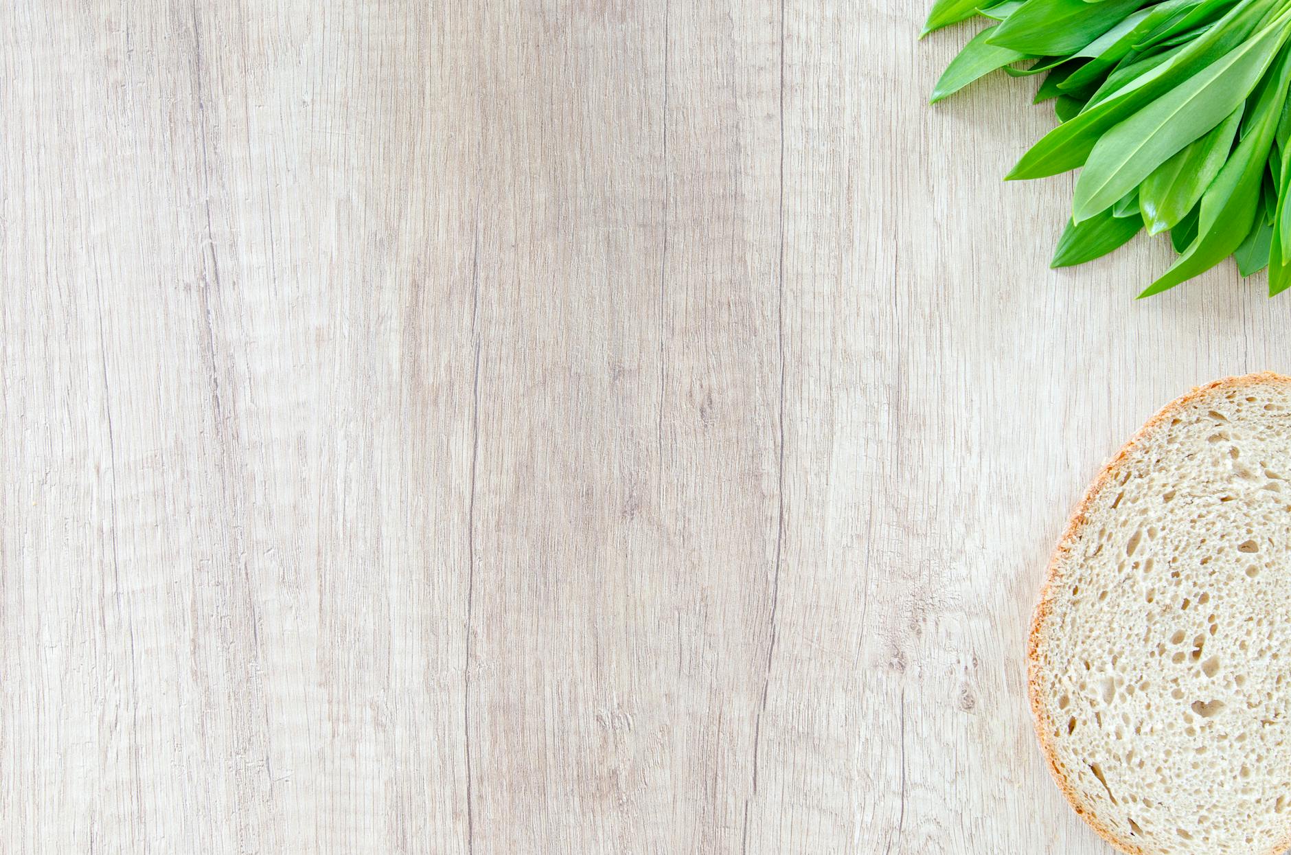 Slice of bread and green leaves on a wooden surface. Perfect for food and health-related content.