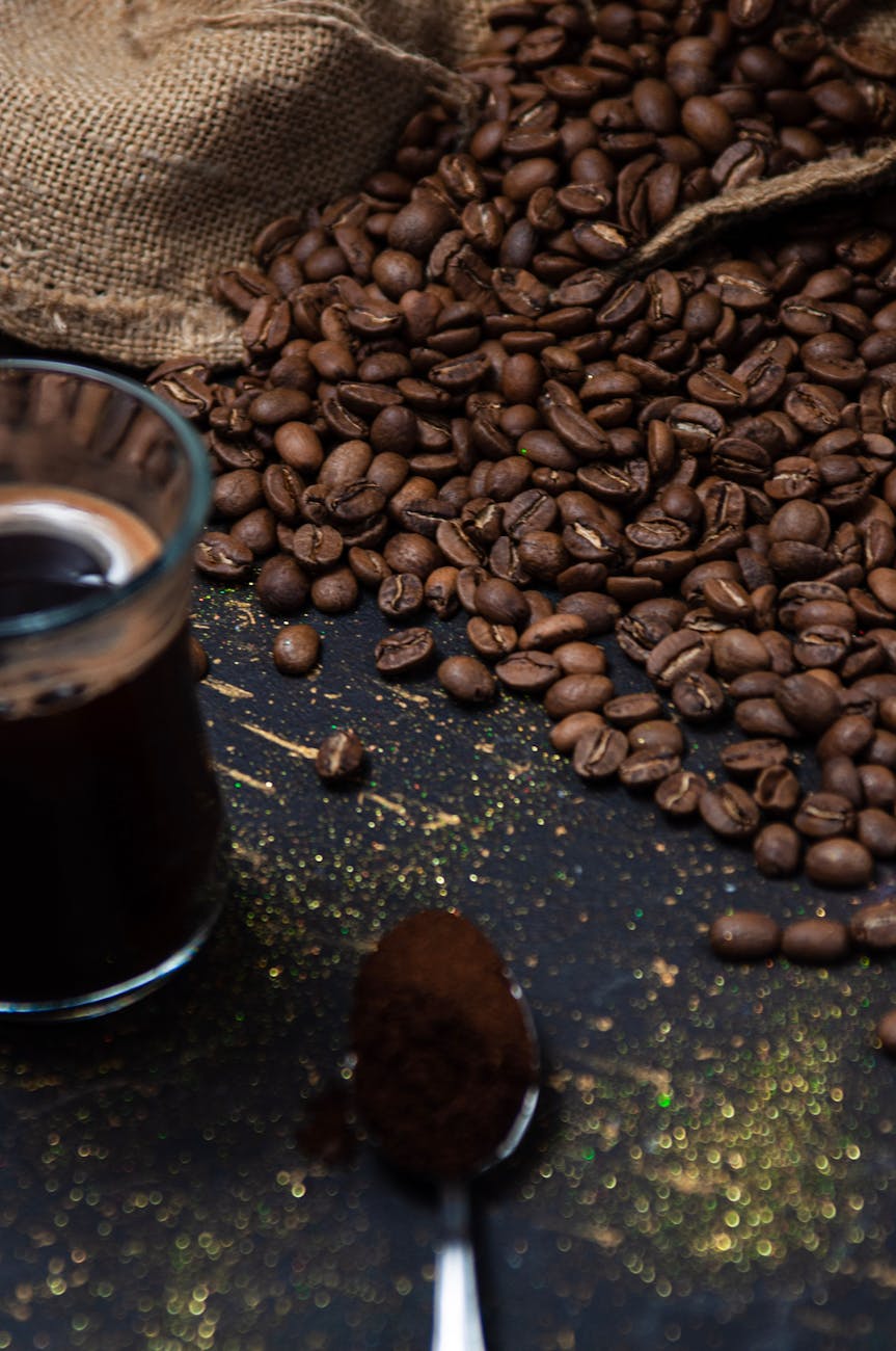 Close-up of roasted coffee beans and black coffee on a dark surface.