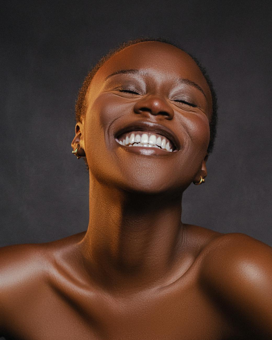 A beautiful close-up portrait of a smiling black woman with radiant skin and joyful expression.