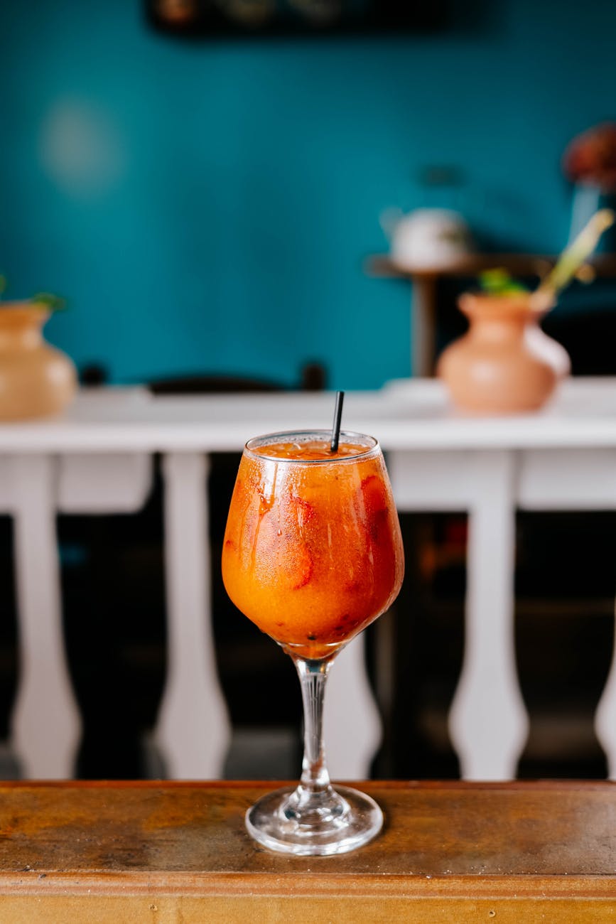 Chilled orange cocktail served in a clear glass with ice and straw, perfect for summer refreshment.