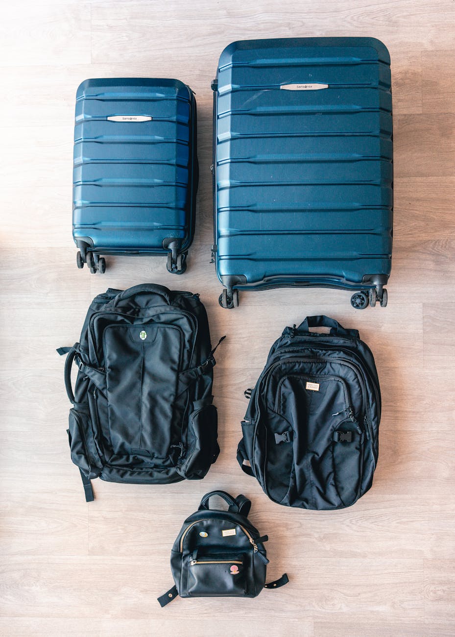 Aerial view of modern luggage and backpacks arranged on a wooden floor.