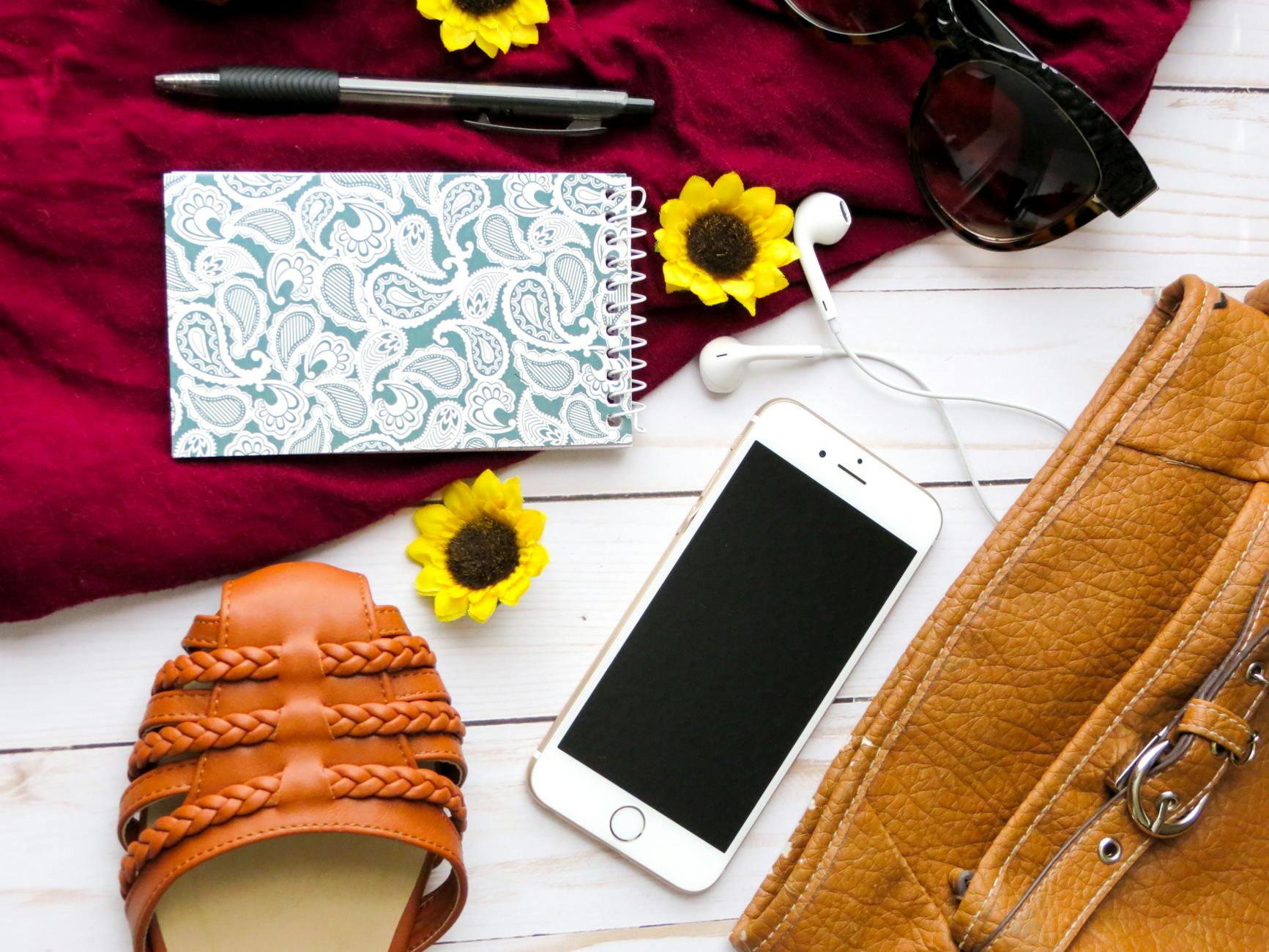 Chic flat lay featuring a leather bag, sunflower accents, and fashion accessories.