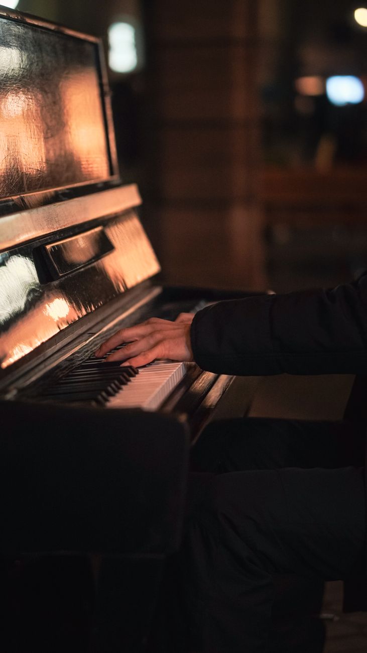 A close-up of hands gracefully playing piano keys in a dimly lit setting.