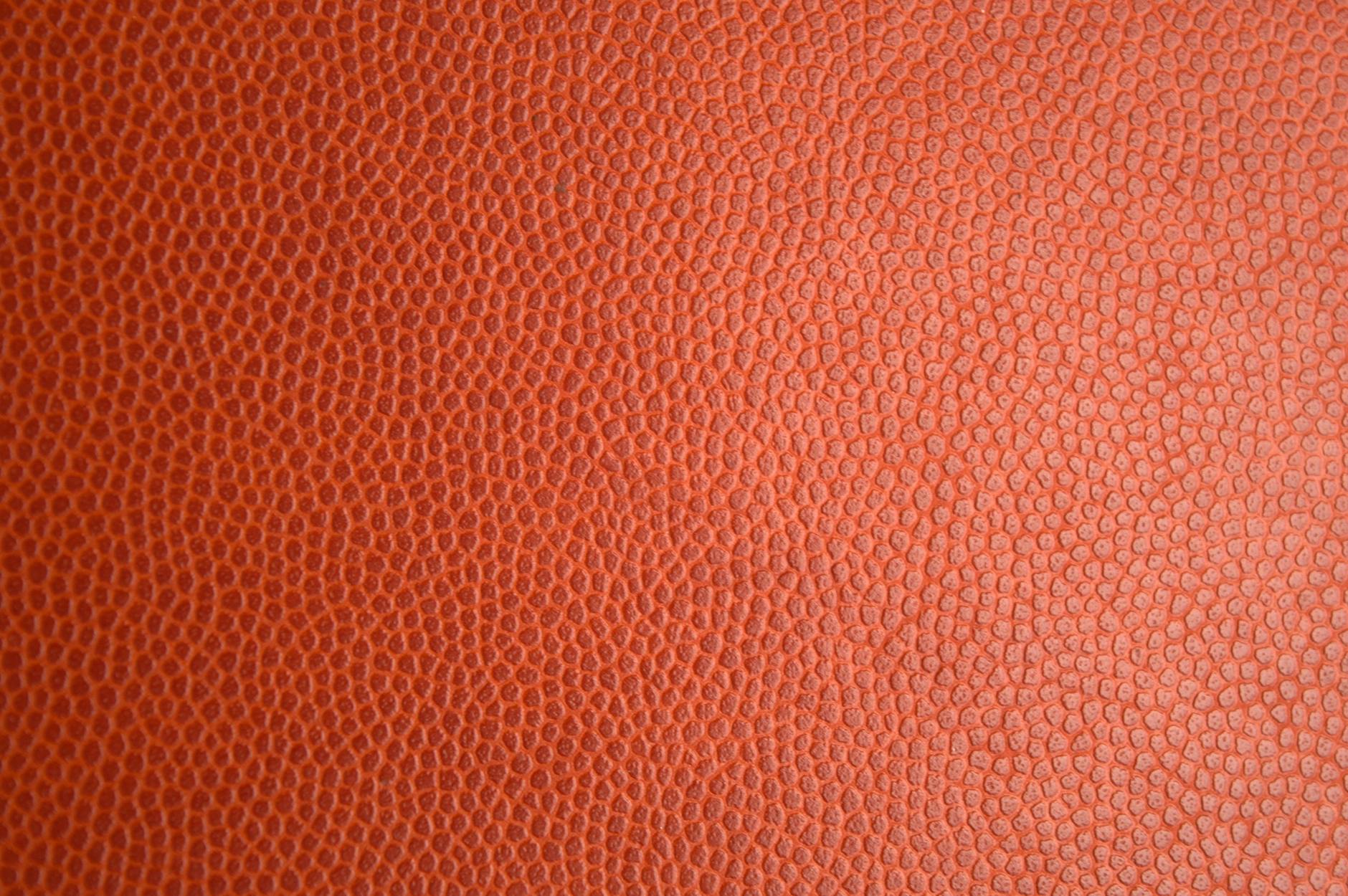 Detailed macro photo of orange leather texture, perfect for backgrounds or materials.
