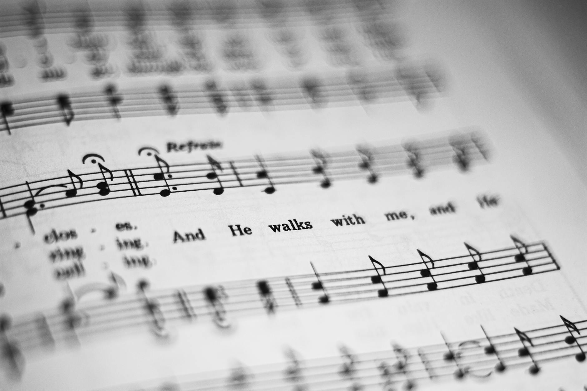 Close-up of black and white sheet music featuring musical notes and lyrics in focus.