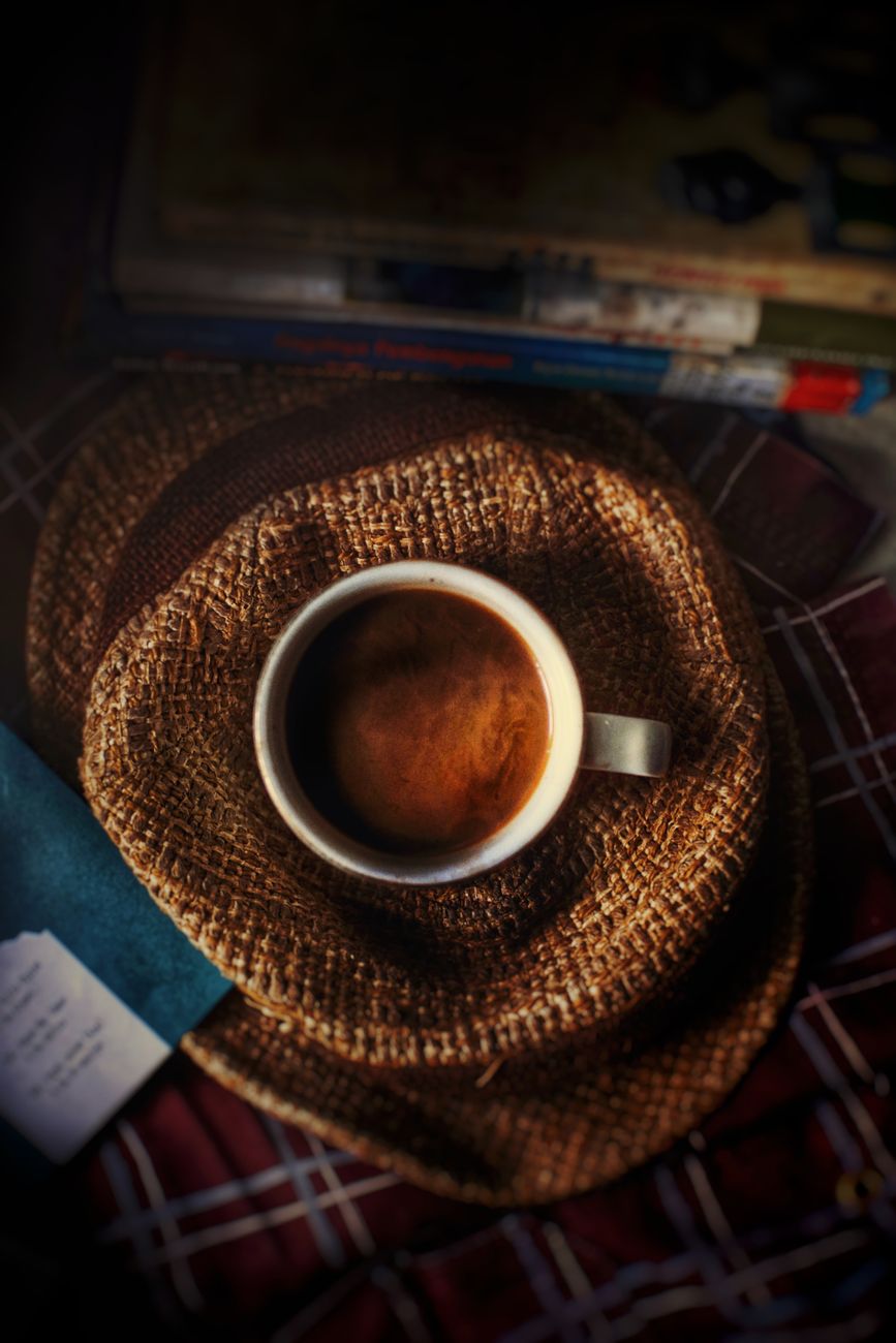 Warm and rustic scene with a coffee cup placed on a straw hat, perfect for relaxation themes.