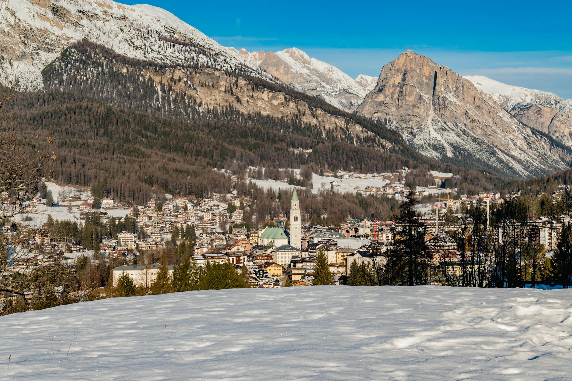 Snowy landscape of Cortina d'Ampezzo with the Dolomite mountains under clear skies.