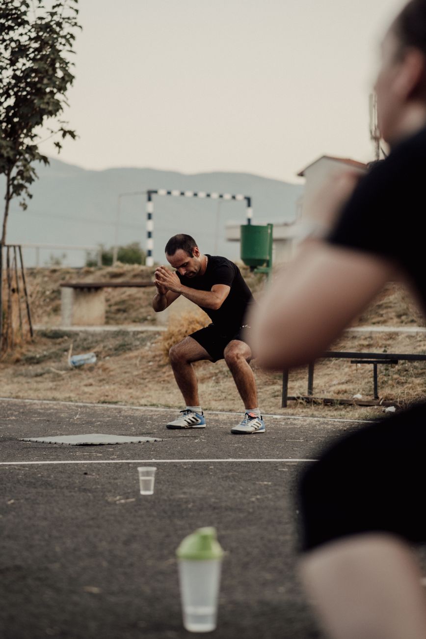 Adults engaging in outdoor fitness activities, performing squats in a park setting.