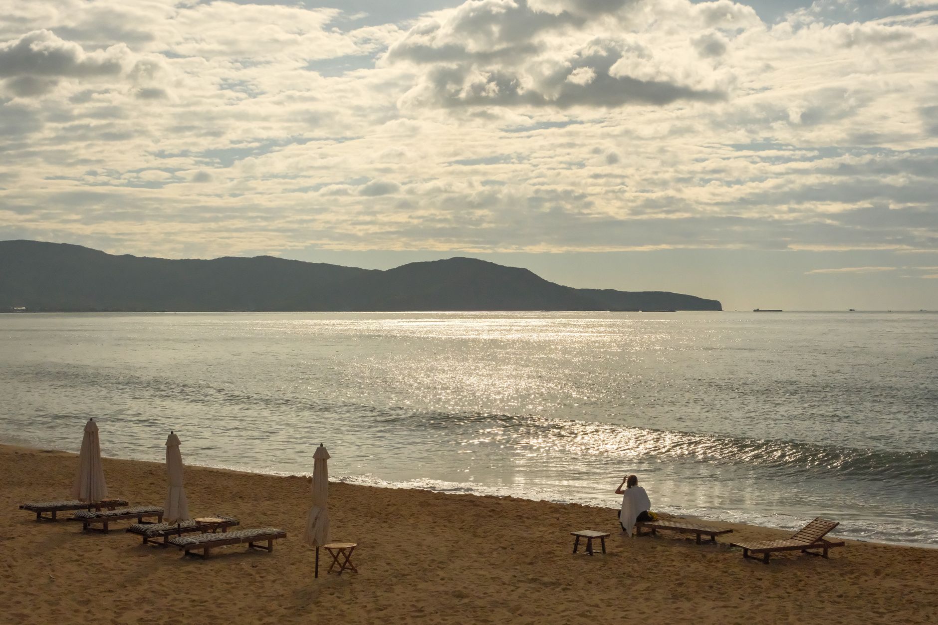 Serene beach scene in Quy Nhon, Vietnam, featuring empty loungers and a scenic coastline.