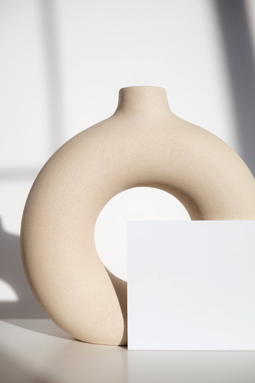 Stylish circular vase on a white surface with soft shadows creating an elegant minimalist effect.