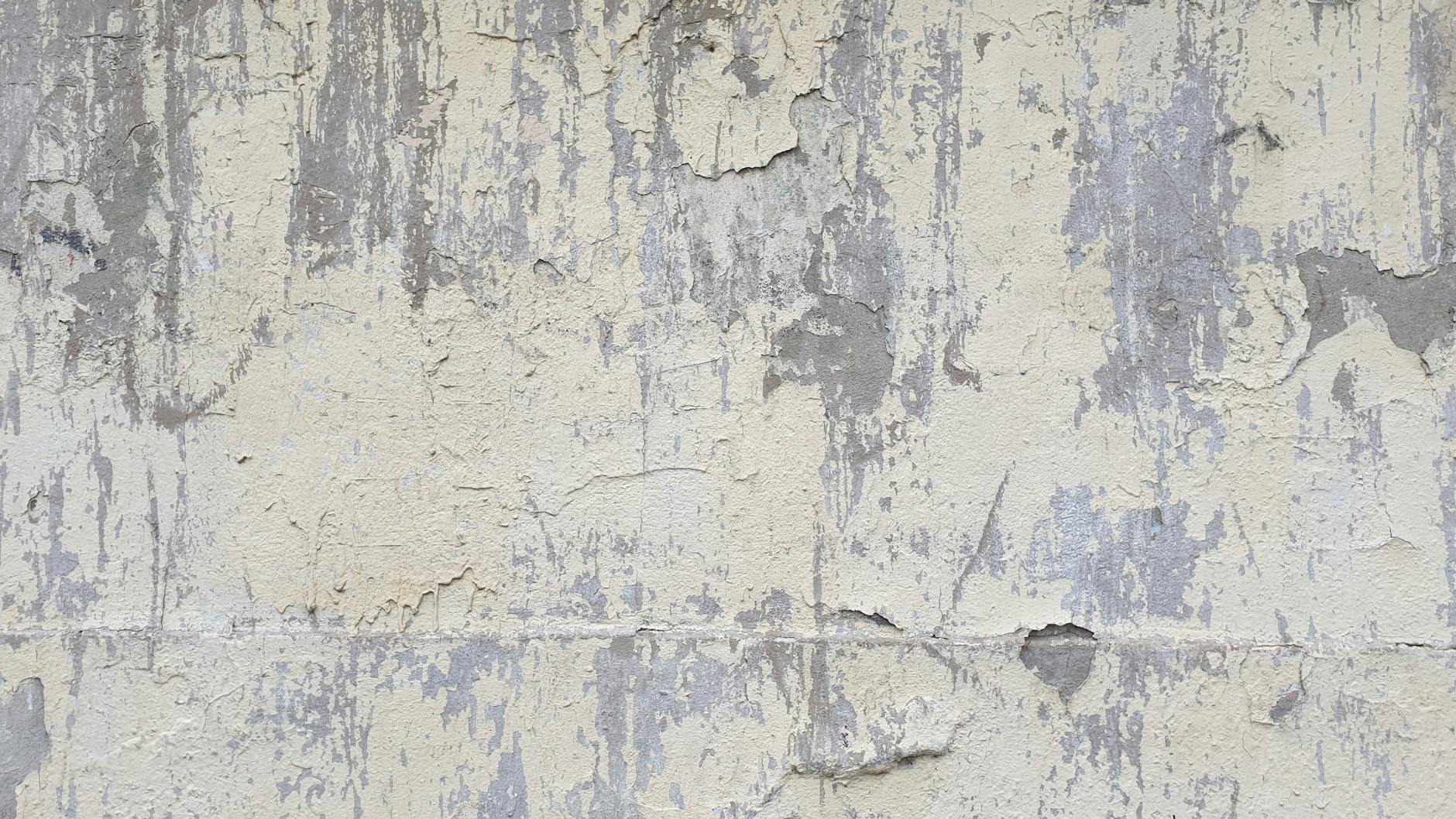 Detailed texture of a weathered concrete wall featuring peeling paint and abstract patterns.