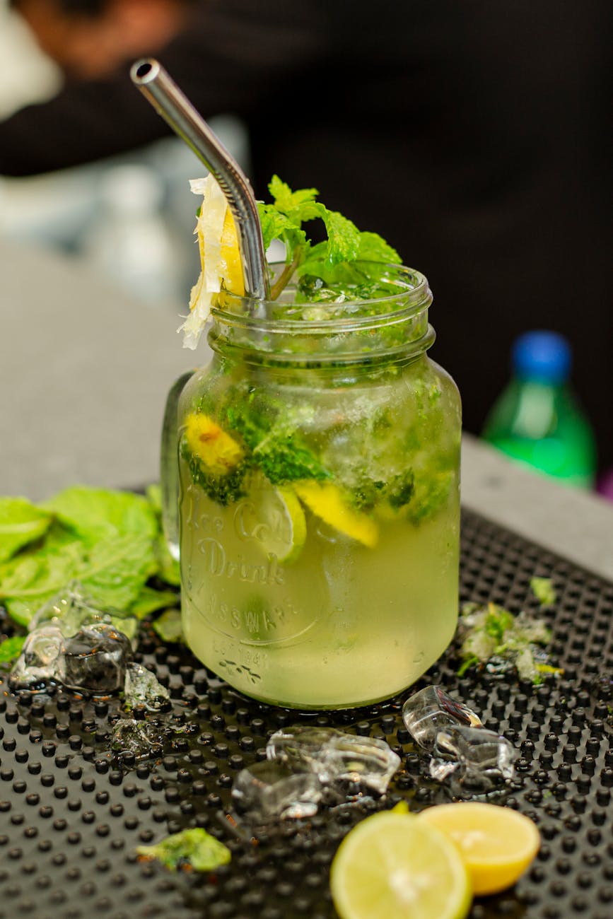A vibrant mason jar mojito with fresh mint leaves, lime slices, and a metal straw.